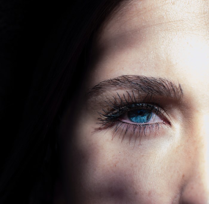 Close-up of a woman's blue eye with dark shadows