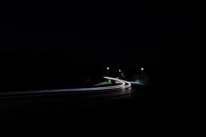 Long exposure of car light trails on a dark road at night