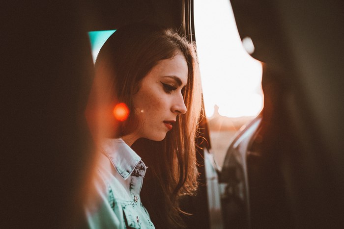 Woman in car during golden hour with sun flare