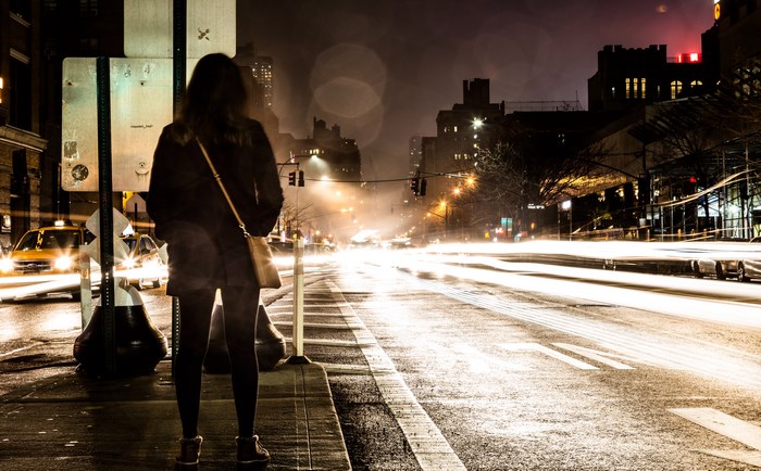 Woman standing on a city street at night with light trails