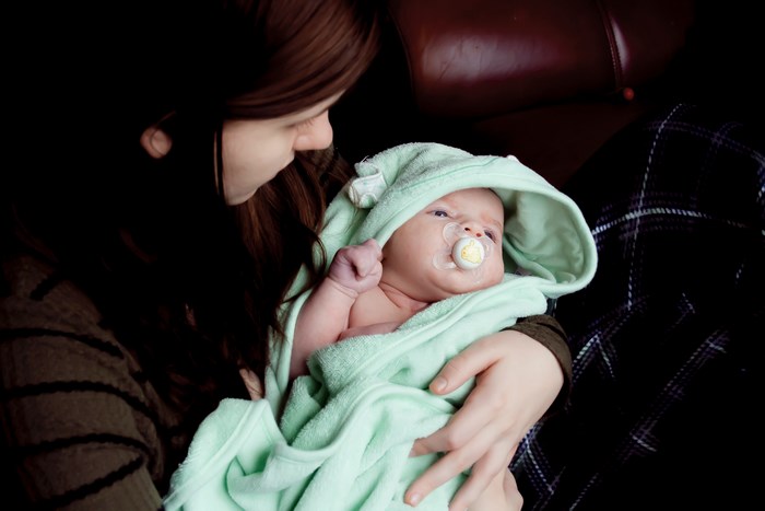 Mother holding a baby wrapped in a green towel