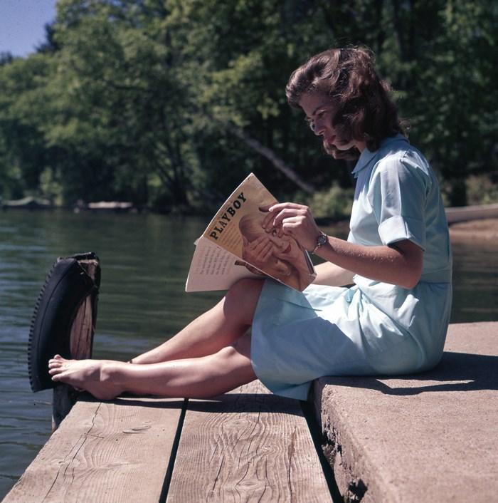 Woman reading Playboy magazine on a jetty