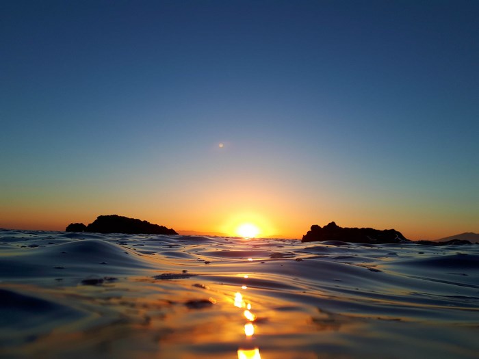 Sunset over the ocean with rocks and ripples