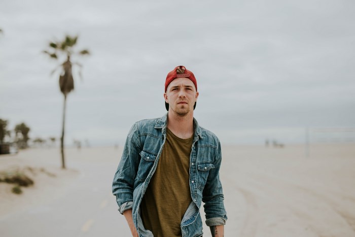 Man in denim shirt and red hat on a beach