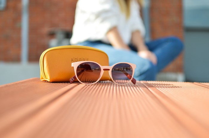 Pink sunglasses and yellow case on a table