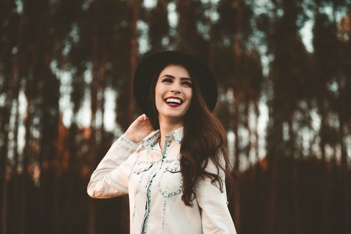 Woman in a hat smiling in a forest