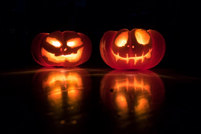 Two carved jack-o'-lanterns glowing in the dark