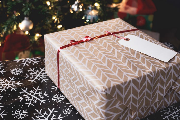Gift box with ribbon and tag near Christmas tree