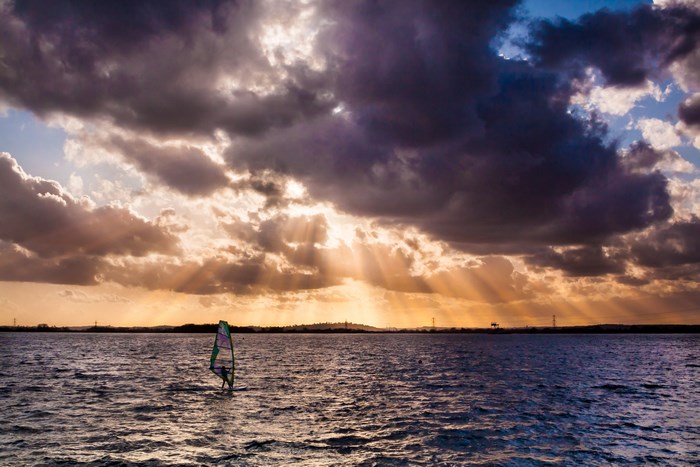 Windsurfer on the sea under dramatic clouds