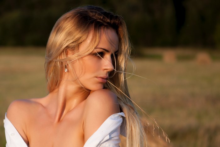 Beautiful blonde woman in a field at sunset
