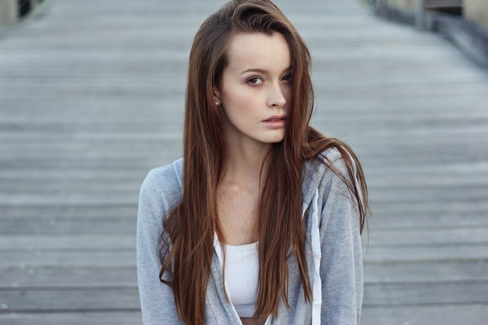 Young woman with long brown hair wearing a grey hoodie