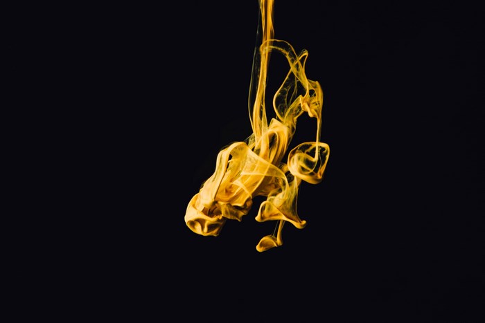Yellow ink dissolving in dark water