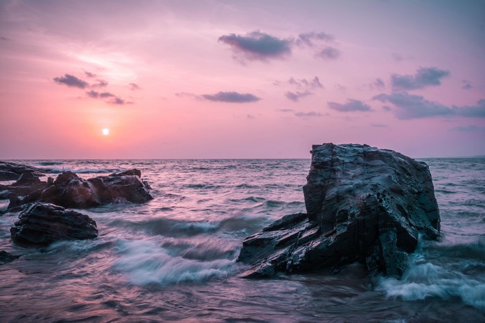 Ocean waves crash against rocks at sunset