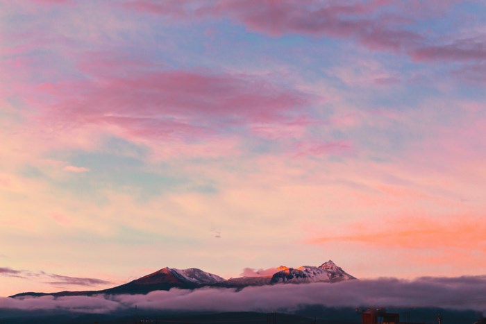 Snow-capped mountains at sunset with pink clouds