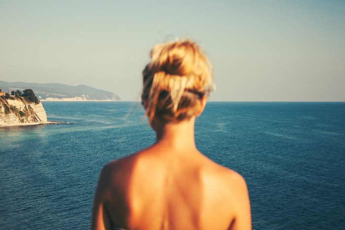 Woman looking out at the ocean from a cliff