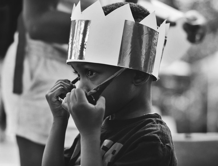Young boy wearing a paper crown and sunglasses