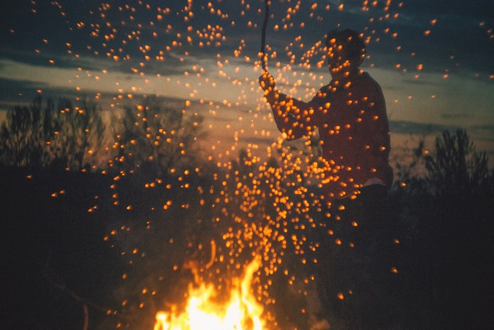 Silhouette by Campfire with Sparks at Night