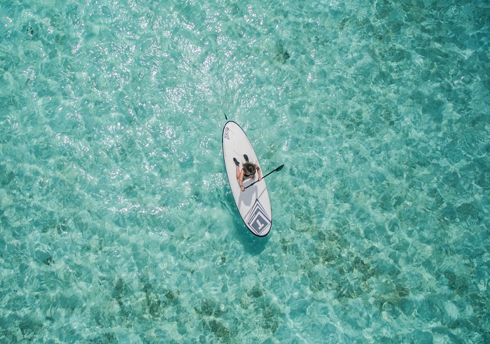 Person paddleboarding on clear turquoise water