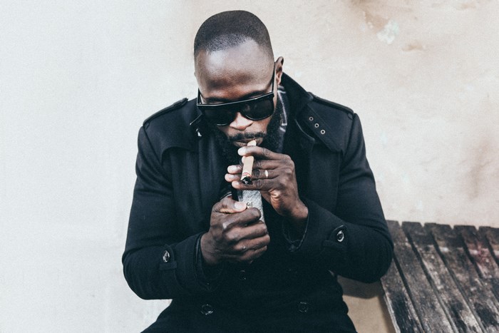 Man in black coat lighting a cigar