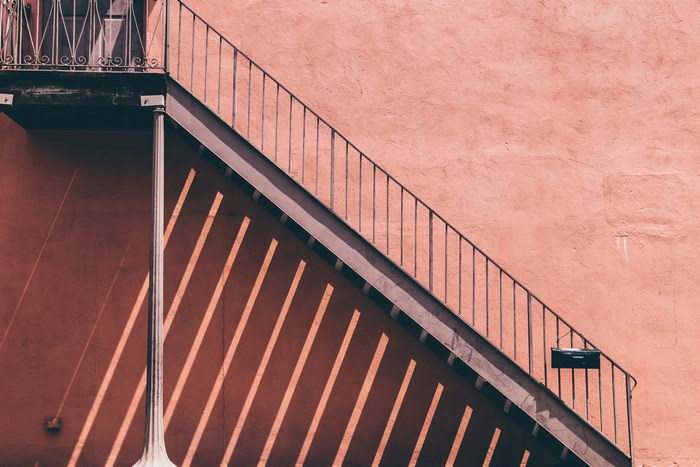 Pink wall with metal staircase and shadows