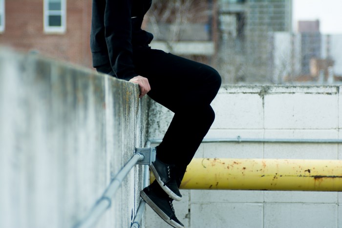 Person in black sitting on a concrete ledge