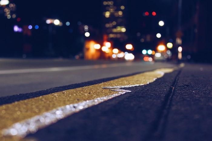 Nighttime city street with yellow lane marker