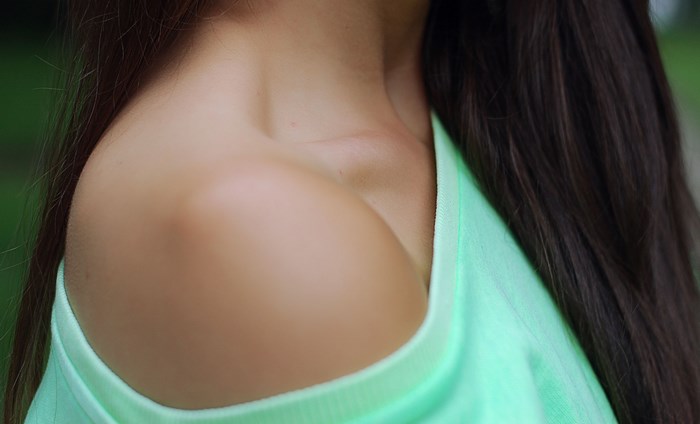 Woman's shoulder and collarbone in a green top