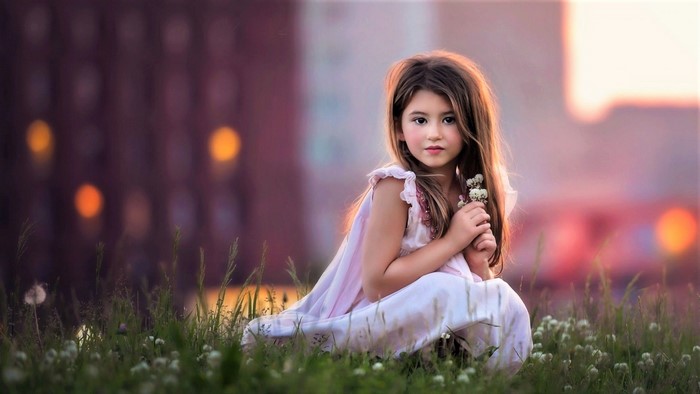 Young Girl Sitting in a Flower Field at Sunset