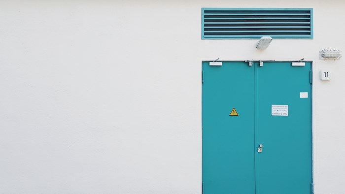 Teal double doors on a white wall with a vent