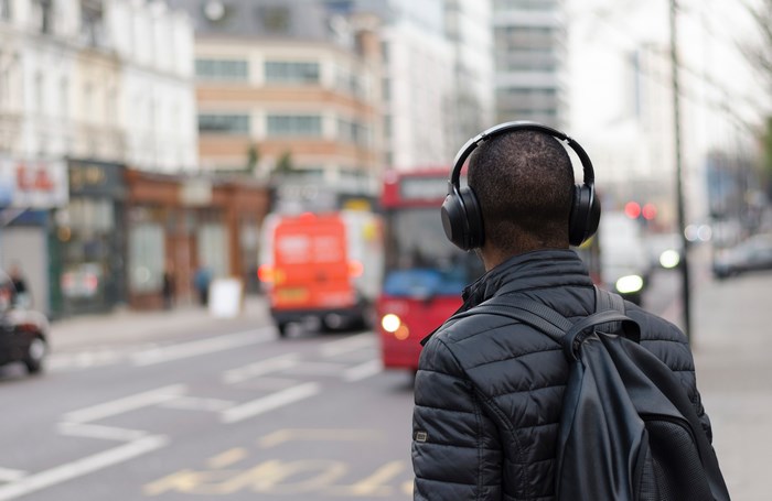 Man with headphones and backpack on city street