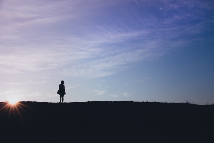 Woman standing on a hill at sunset