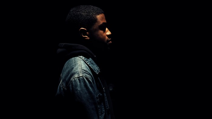 Man in denim jacket and hoodie in profile