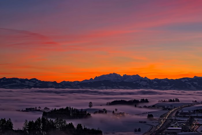 Mountain range at sunrise over fog and forest