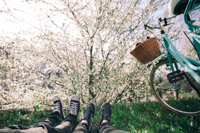 Couple's feet and bicycle under blooming tree
