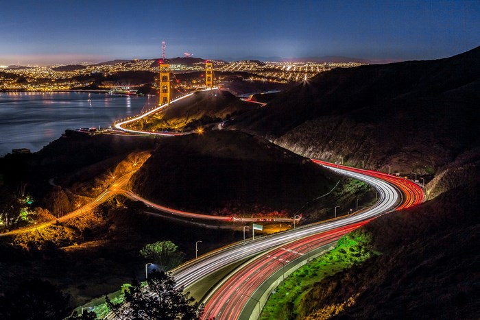 Golden Gate Bridge at night with light trails on highway