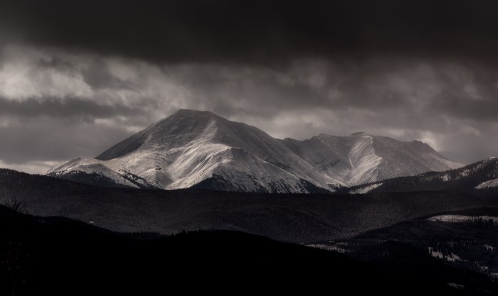 Snow-capped mountain range under storm clouds