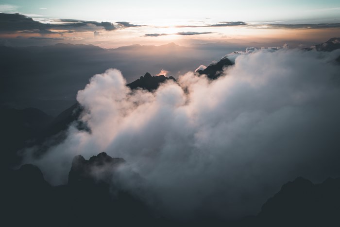 Mountain peaks emerge from clouds at sunrise