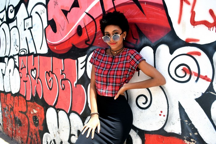 Woman in plaid shirt against graffiti wall