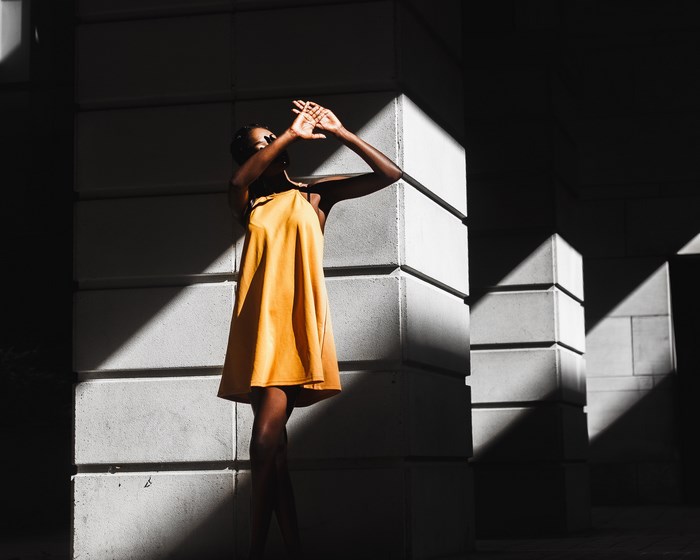 Woman in yellow dress standing in shadows and light