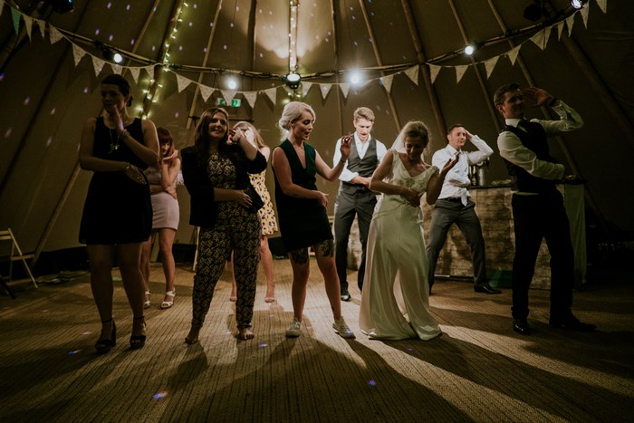 People dancing at a wedding reception in a tent