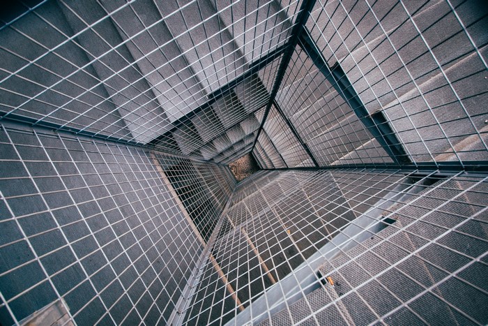 Looking down a modern steel stairwell with a cage structure