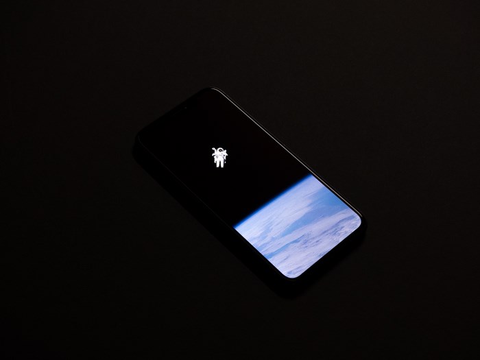 iPhone X with astronaut and Earth wallpaper