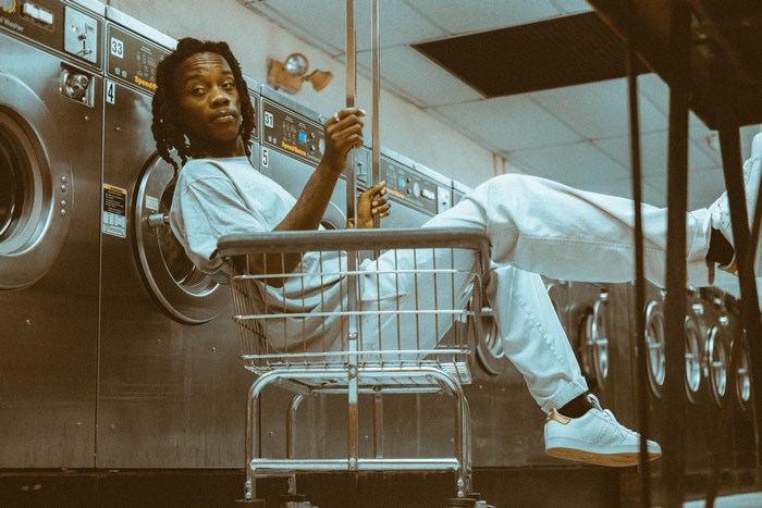 Man sitting in a shopping cart at a laundromat