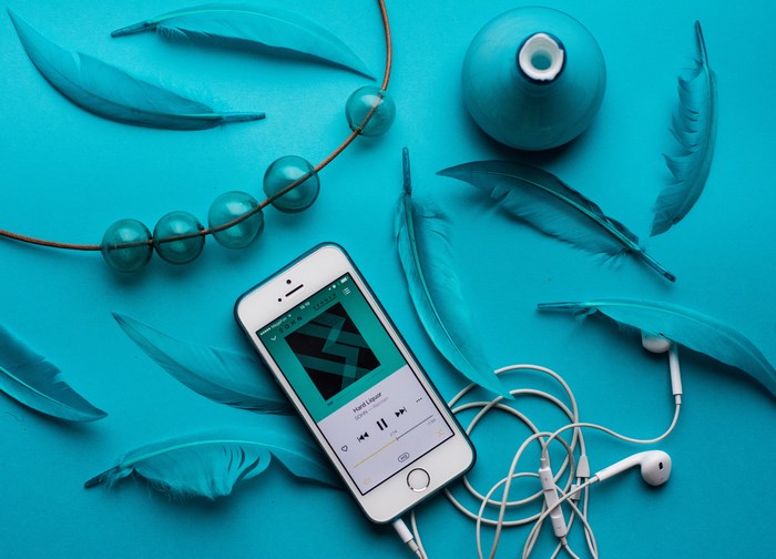 iPhone with Yandex Music app, feathers, and beads