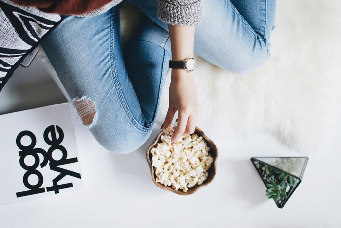 Woman eating popcorn next to a book and succulent