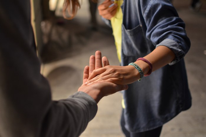 Two people holding hands, one wearing a denim shirt