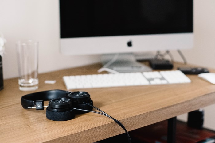 Apple iMac computer with headphones on a wooden desk