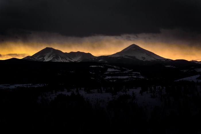 Silhouette of snow-capped mountains against a golden sky
