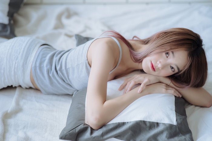 Asian woman lying on a bed with pillows