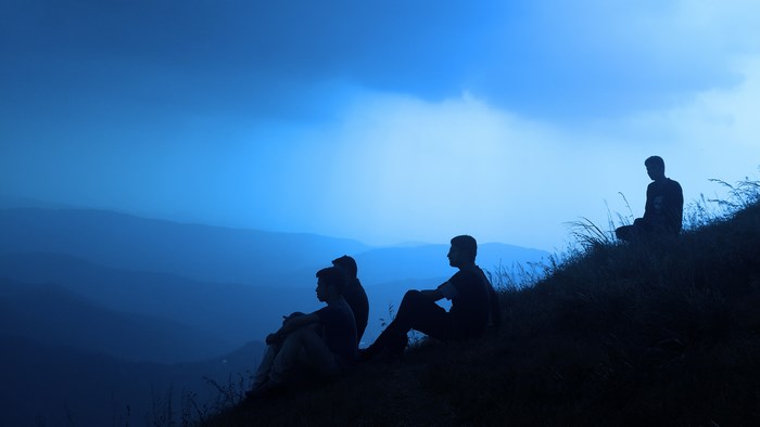 People sitting on a hillside at twilight